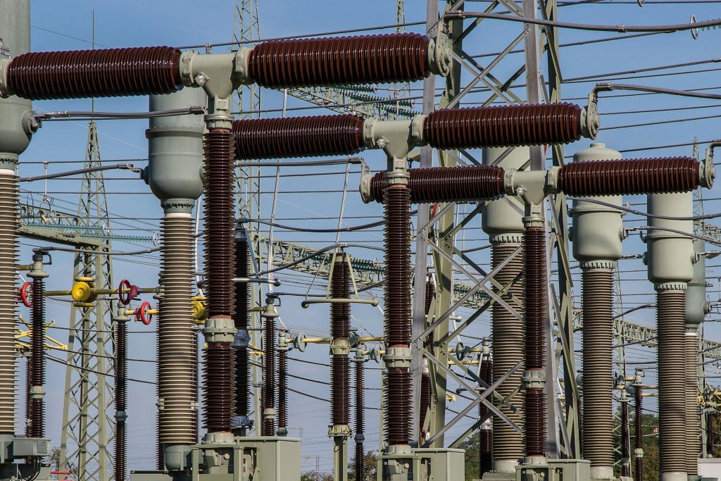 Electrical substation with high-voltage insulators and transmission infrastructure representing utilities and energy economic impact analysis